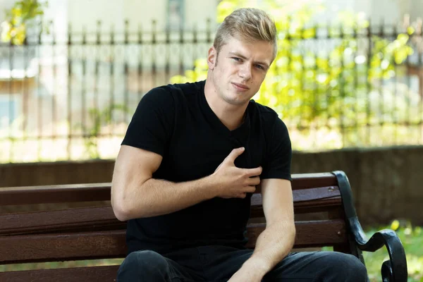 Outdoor portrait of a  man  with heart attack or broken heart  standing in the park