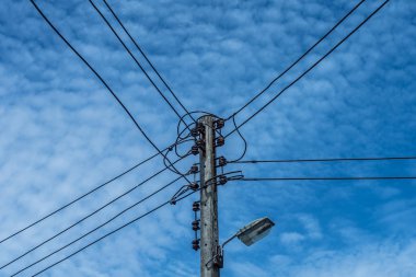 Elektrikli tel ve lamba mavi bulutlu gökyüzü arka plan ile elektrik kutup