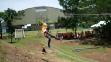 Güvenli olması için kask takan, halatla asılan insanların bulanık görünümü. Güneşli bir günde heyecan verici bir açık hava macera aktivitesi.