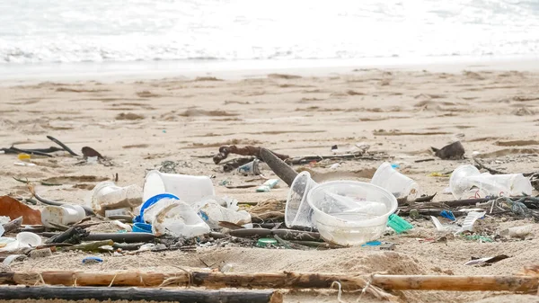 Environmental pollution. Ecological problem. Garbages, plastic, and wastes on the sandy beach of tropical sea.