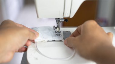 Kumaş ve iplikli elektrikli dikiş makinesi, koruyucu maske üzerindeki odaklanma azalması, COVID-19 salgını sırasında antivirüs maskesi.