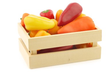 beyaz bir arka plan üzerinde tahta bir kutu içinde karışık kırmızı, turuncu ve sarı tatlı snack biber