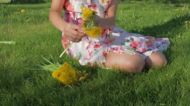 Çim ve çiçek karahindiba örgüler A çelenk üzerinde oturan bir kadın close-Up