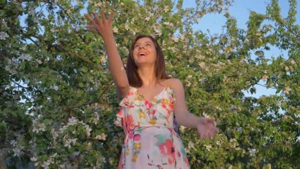 Donna sta in un rigoglioso fiore Frutteto di mele e lancia petali di fiori — Video Stock