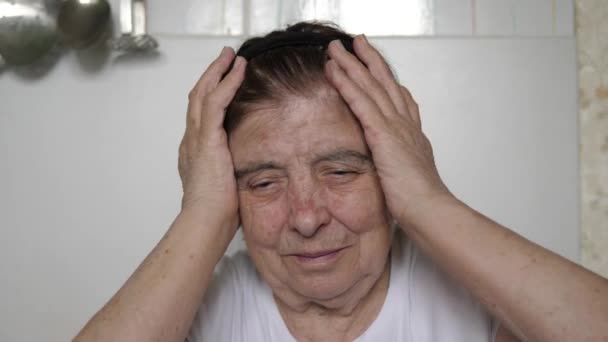 Een oudere oude vrouw heeft een ernstige hoofdpijn — Stockvideo