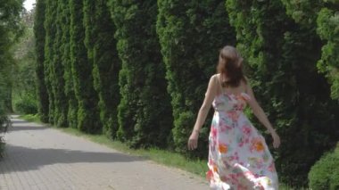 Kadın elbiseli bir dekoratif selvi sokak güneşli bir yaz günü çalışır.