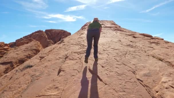 Een vrouw klimt de berg op de monolithische rode rots — Stockvideo