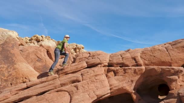 Bir kadın kırmızı tırmanıyor yan görünümü arka plan gökyüzü kayalar. — Stok video