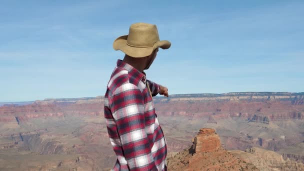 人在大峡谷的背景点他的手在岩石纪念碑 — 图库视频影像