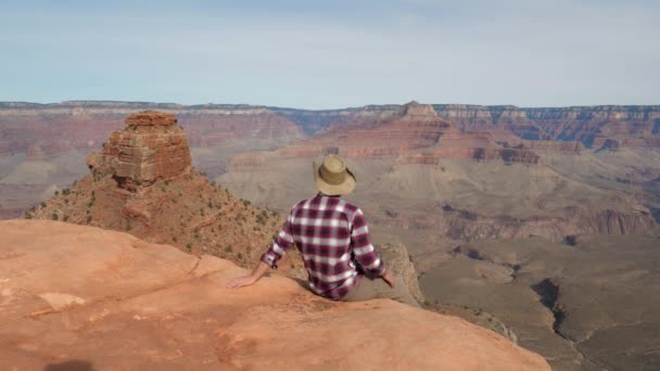 Kaukasier sitzt am Rande des Abgrunds und blickt auf den Grand Canyon — Stockvideo