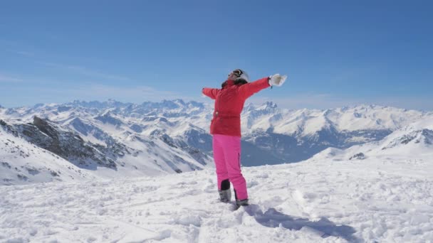 Skier жінка піднімає зброю і поворот потім вона падає на сніг фоні гори — стокове відео