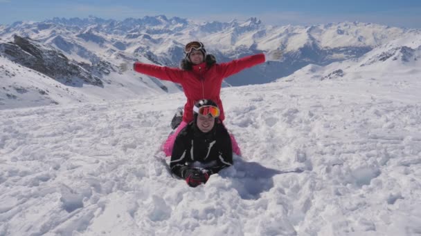 Горнолыжный курорт Красивая пара лыжников, лежащих на снегу поднять руки — стоковое видео