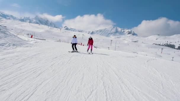 Dos esquiadoras esquiando por la ladera ideal de la montaña en invierno — Vídeos de Stock