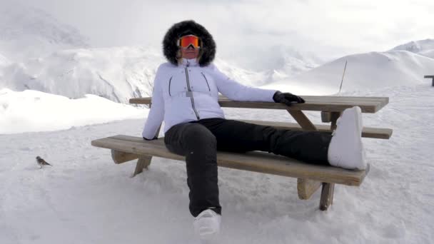 Plaisir de skieur de femme se détendre dans les montagnes assis sur le banc — Video