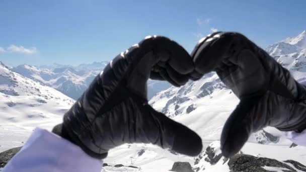 Las manos femeninas haciendo la forma de dedo de un signo de corazón en una impresionante vista de las montañas — Vídeos de Stock