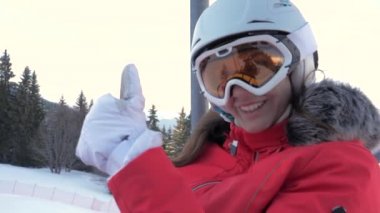 Mutlu kadın kayakçı Ski Lift tırmanıyor ve parmağını çıkar ortaya