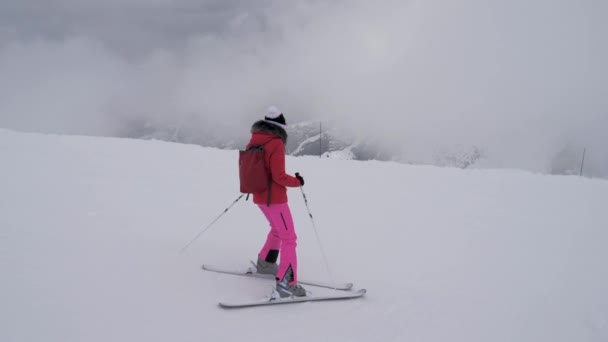 Mulher esquiador esqui descendo a encosta da montanha em um nevoeiro pesado — Vídeo de Stock