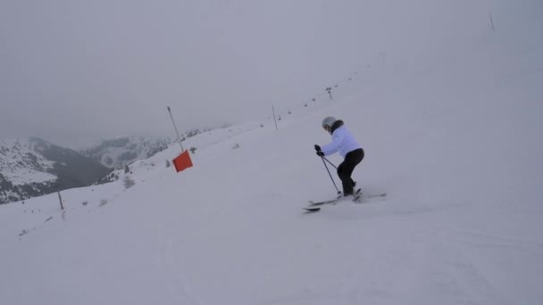 Катание на лыжах по склону в горах зимой в тумане — стоковое видео