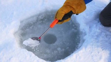 Balıkçı el kepçe delik buz kış balıkçılık için temizler.