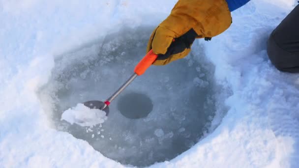 Balıkçı el kepçe delik buz kış balıkçılık için temizler. — Stok video