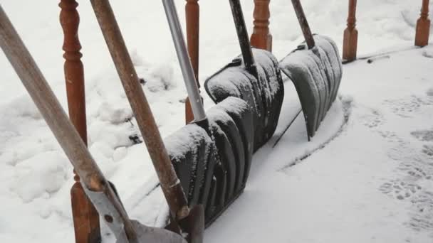 Veel schoppen permanent op de veranda van het huis In de zware sneeuwval In de Winter — Stockvideo