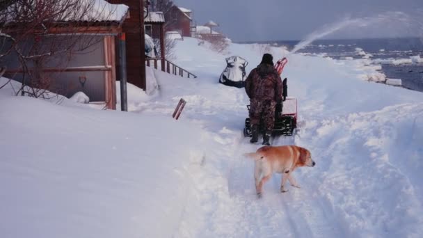 Человек очищает снежную машину от снега зимой — стоковое видео