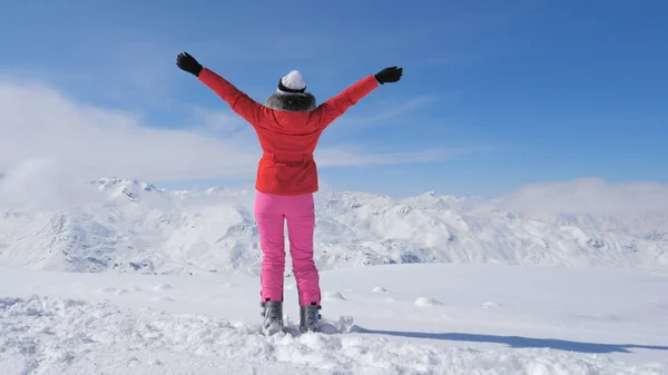 En yüksek dağ, bir şık kayakçı kadın yükseltir eller