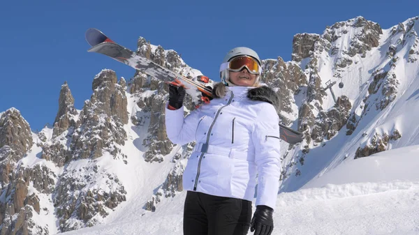 Kadın kayakçı omzuna kayaklar ile dağlarda doğanın güzelliği hayran