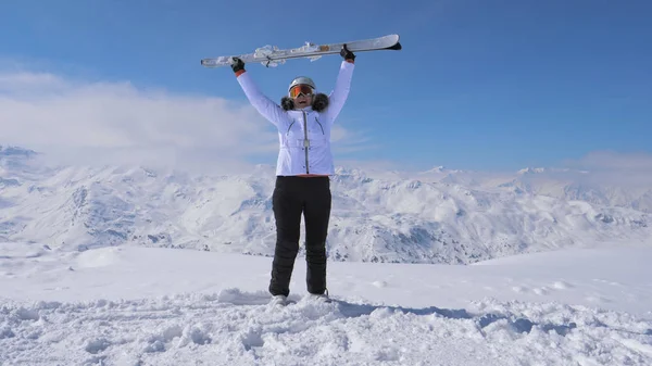 Kadın kayakçı Kayak kaldırdı yamaç dağda duruyor ve onları dalgalar