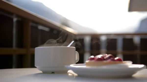 Sıcak bir içecek beyaz bir fincan ve bir tabak Cafe'de tatlı ile