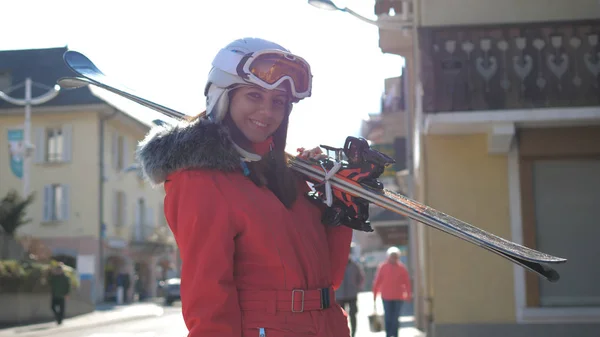 Attractive Woman Stands Near Houses Holding Her Downhill Ski Before Skiing Stock Image