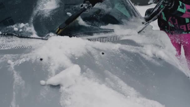 Mulher limpa ativamente seu carro da neve no inverno com uma escova — Vídeo de Stock