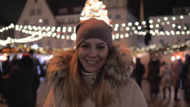 Mujer sonriente feliz de pie en el mercado de Navidad con hermosas iluminaciones — Vídeo de stock