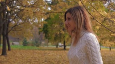 Sonbaharda parkta yürüyen bir kadın yan görünüm onun baş ve gülümsüyor döner