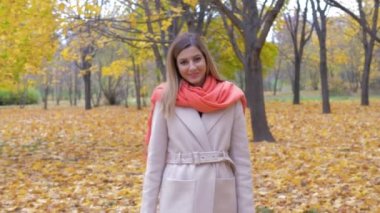 Sarı yapraklar ile sonbahar parkta yürüyen mutlu gülümseyen kadın