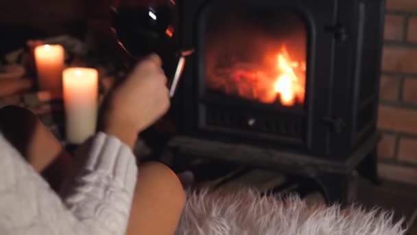 Einsame Frau sitzt vor dem Kamin und trinkt Wein aus einem Glas — Stockvideo