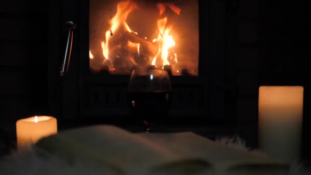 Şöminede yanan yakın alev yanan mumlar ve açık bir kitap yatıyor — Stok video