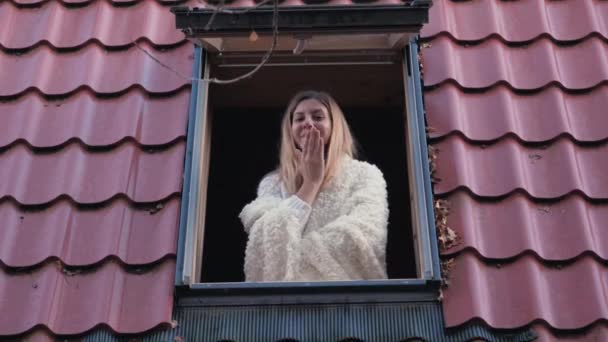 Gelukkig lachende vrouw In het venster thuis kijken Camera en een kus verzenden — Stockvideo