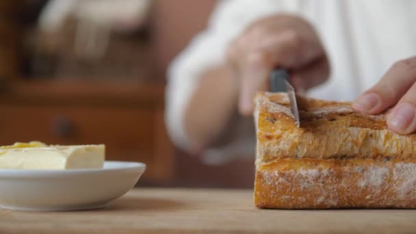 Gros plan des mains des femmes avec un pain coupé au couteau et du beurre à tartiner dessus — Video