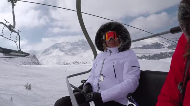 Лыжник забирается на стул, поднимается на вершину горы и машет рукой, приветствуя — стоковое видео