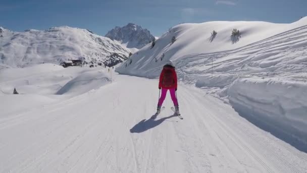 在运动中 滑雪者穿着鲜艳的衣服在高山滑雪胜地滑雪 阳光明媚 雪闪闪发亮 天气晴朗 动作慢 — 图库视频影像