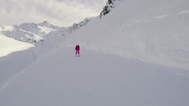 Kvinna skidåkare skidåkning utförsåkning på sluttningen på vintern och driver pinnar — Stockvideo