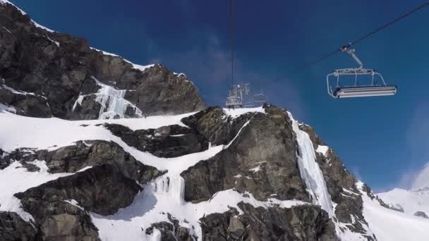 Крісельна канатна піднімається на вершину гори зі скелі в зимовий гірськолижний курорт — стокове відео