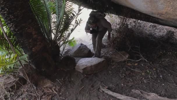 Maduro mulher turista agachado para baixo para sair da caverna fora — Vídeo de Stock
