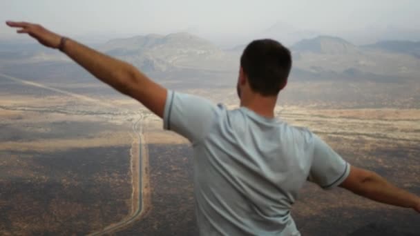 Hombre en la cima de la montaña Manos a los lados y representa el vuelo — Vídeos de Stock