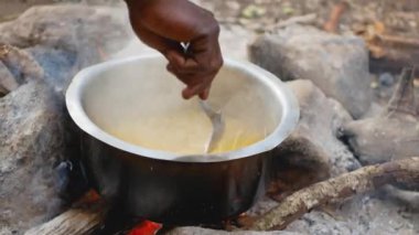 Afro-Amerikan el ile kaşık karışımı makarna ateşte bir tencerede close-Up