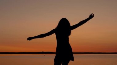 Sunset Beach kadar kollarını yükselterek ve iplik için mutlu bir kadın çalışır