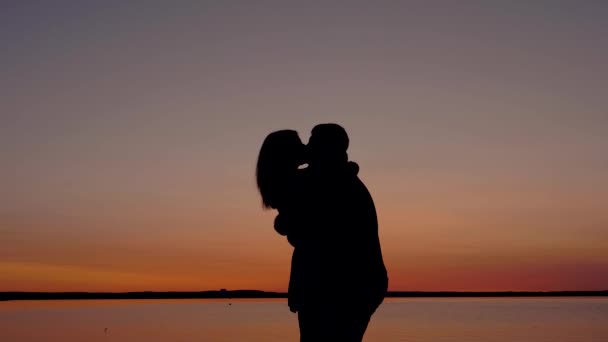 Silueta milující pár mužů a žen, líbání a mazlení při západu slunce — Stock video