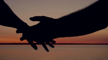 Yakın çekim gün batımında, erkekler Ellerini yavaşça kadın almak eller, şefkatle dokunma ve parmaklarını inme, sonra birbirinden ağır çekim bırak