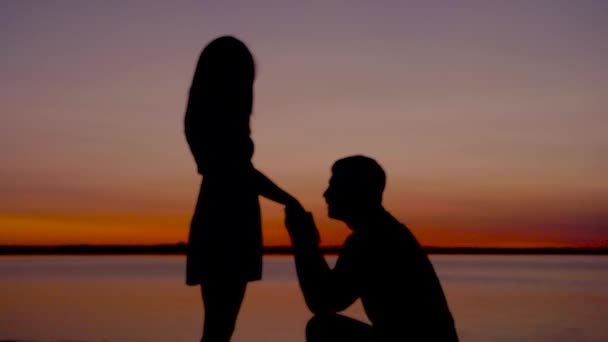 Silhouette Of A Man Sit Down On His Knee And Puts The Ring On The Woman Hand — Stock Video